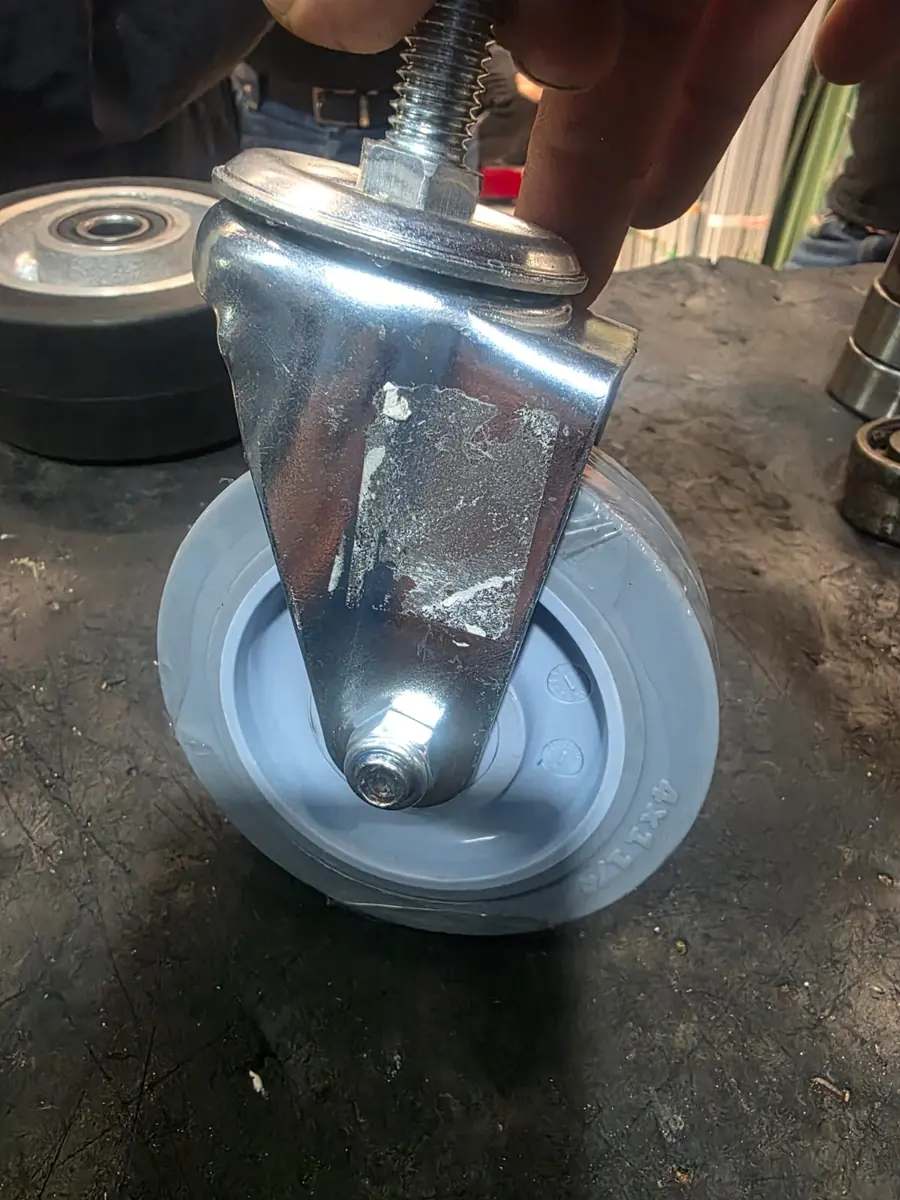 Rueda giratoria gris con espiga roscada en mano